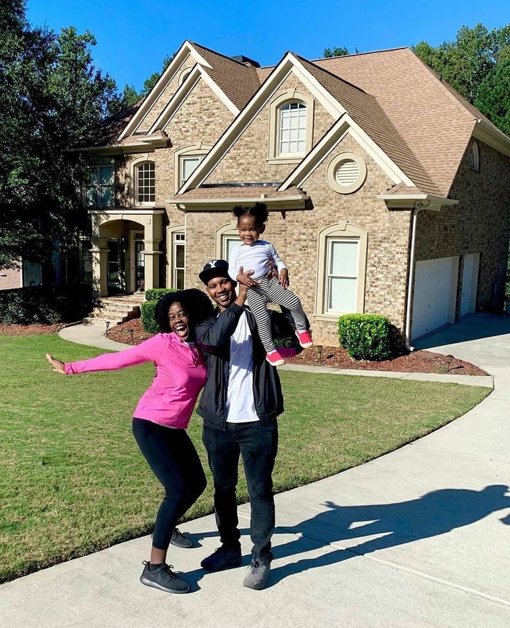 A family celebrating in front of their new home